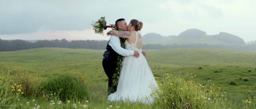 Bride and groom kissing in a field